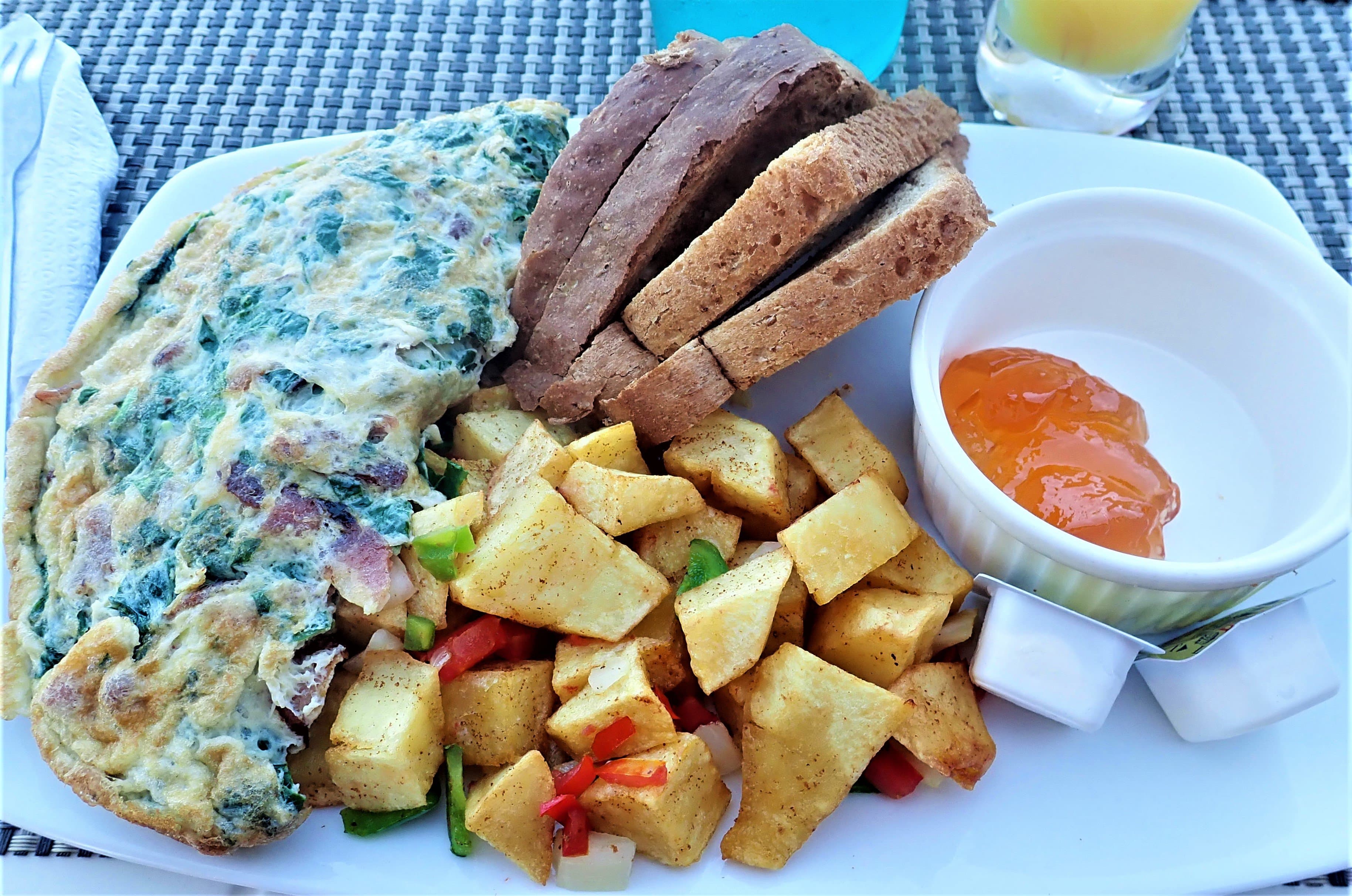 Bacon, callaloo, and cheese omelet, potatoes, toast and guava jelly